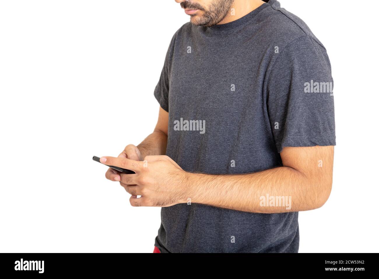 Young man wearing a blank gray t shirt lookina at his mobile phone isolated against white background. Casual male apparel, advertise template Stock Photo