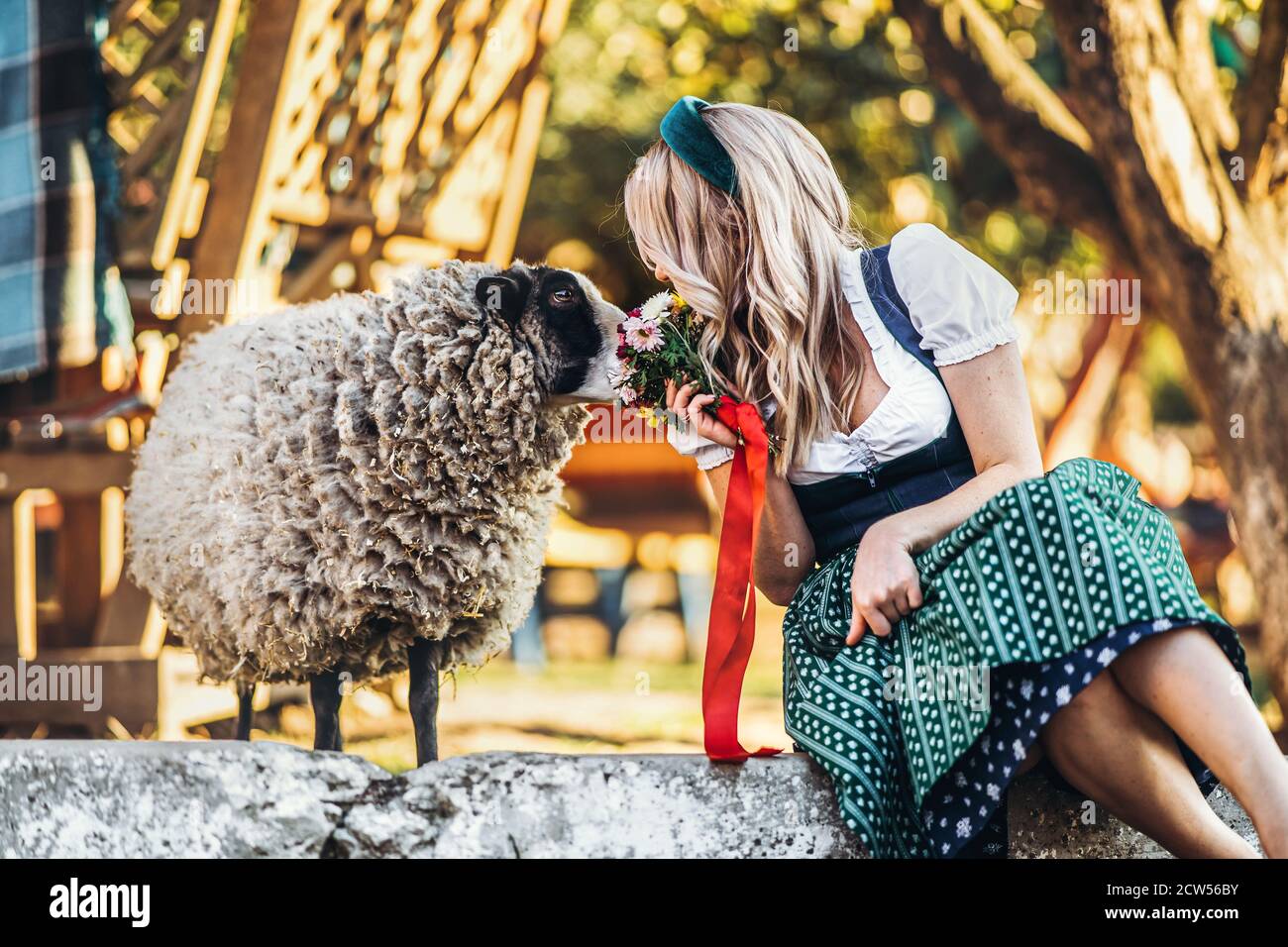Blonde girl in traditional oktoberfest dress with bouquet of flowers ...