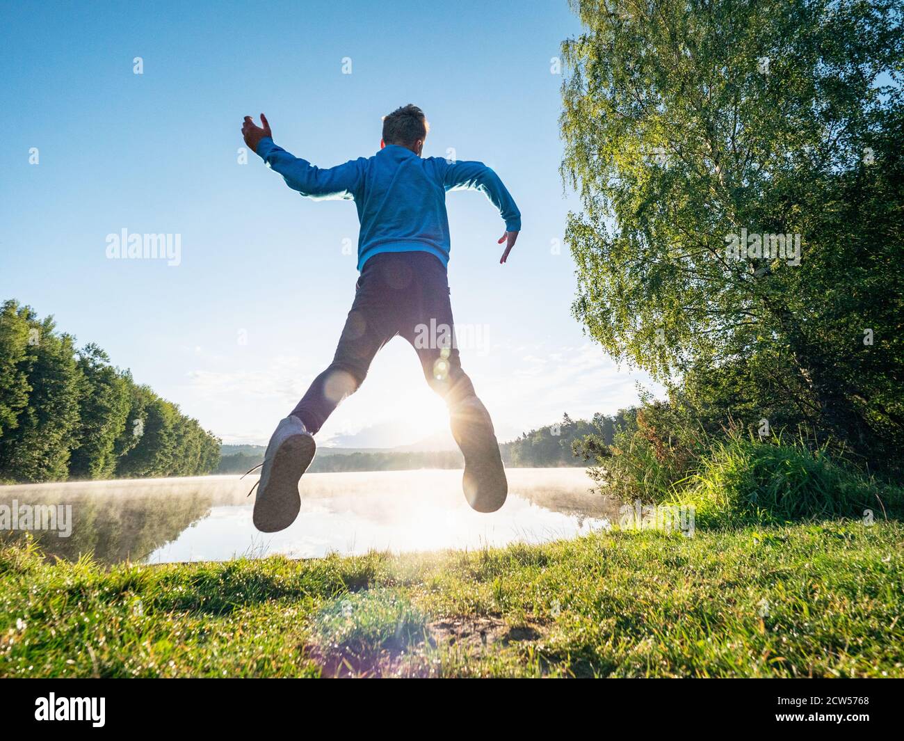 Crazy jumping boy celebrate freedom and make a fun at lake. Crazy and amazing childood Stock Photo