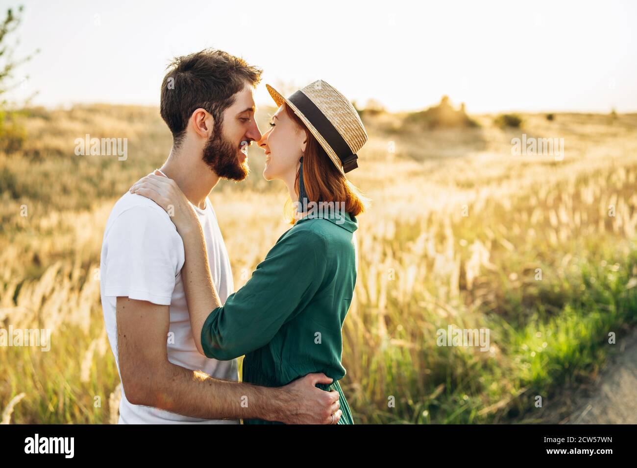 Happy young man and woman smiling and hugs outdoor at sunset. Concept of people, love and lifestyle. Stock Photo