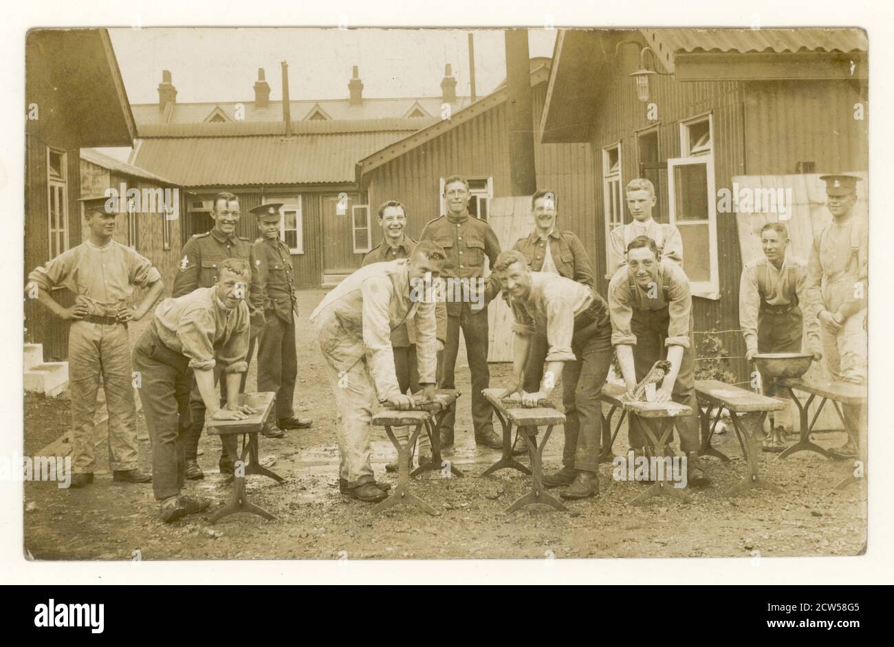 Original WW1 era postcard, during the early part of the war, of cheerful, happy young recruits scrubbing down benches at a training camp, possibly members of the Hampshire Regiment, at Aldershot Camp, Hampshire, U.K. circa 1914 1915 Stock Photo