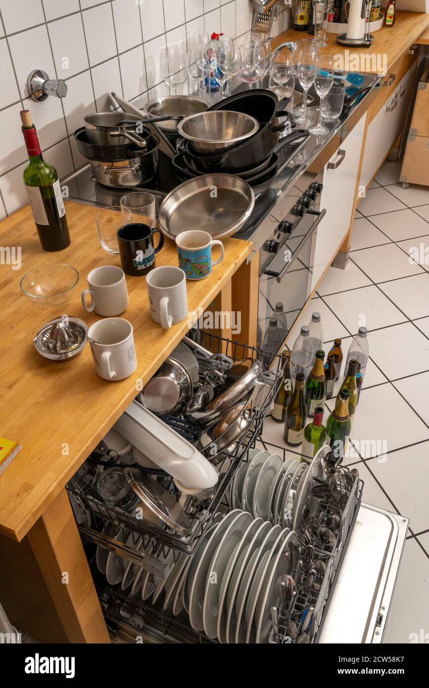 Kitchen after a larger dinner, cooking party, dishwasher, full, with cleaned dishes, dirty glasses, pots, cooking utensils on the sink, waiting to be Stock Photo