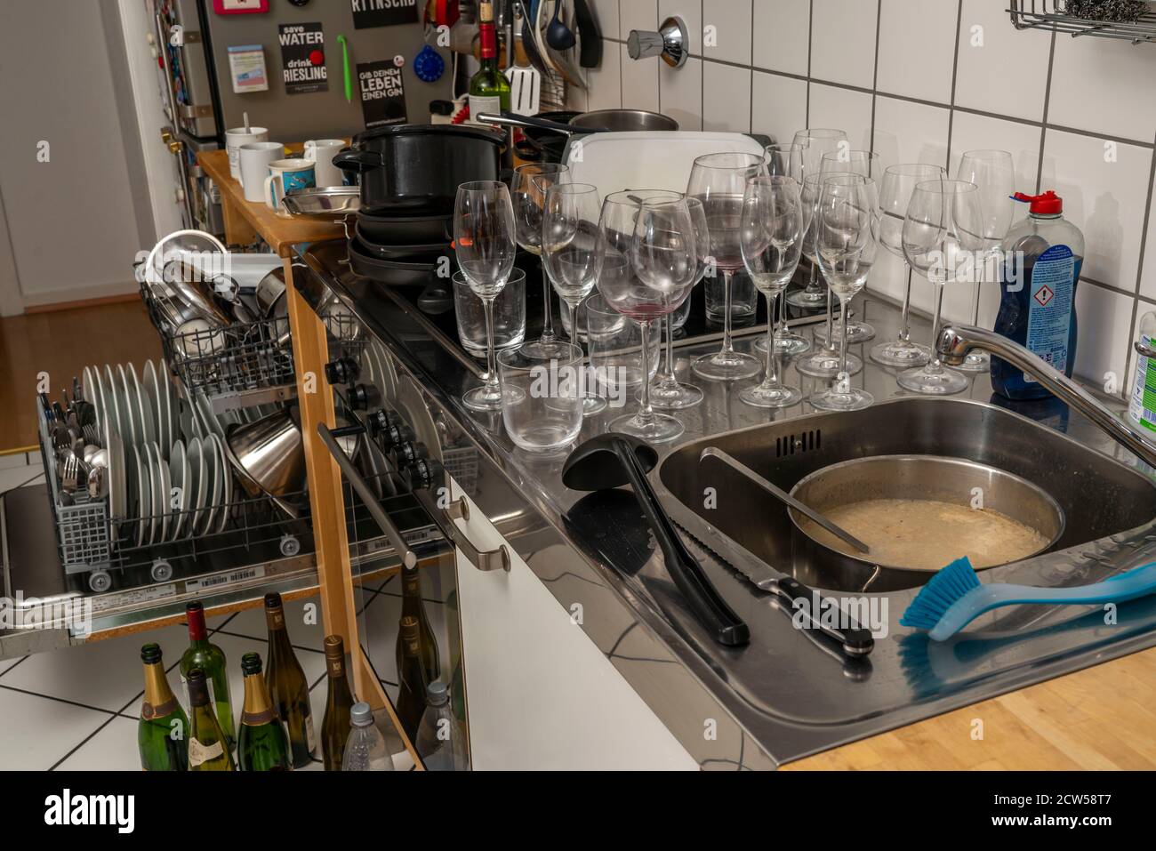 kitchen after a larger dinner, cooking party, dishwasher, full, with cleaned dishes, dirty glasses, pots, cooking equipment on the sink, was Stock Photo