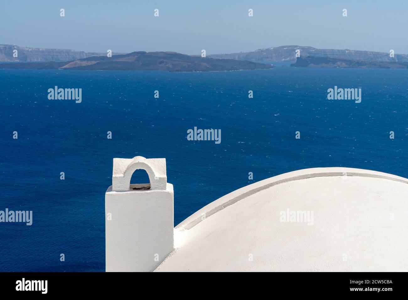 White roof with chimney on the Caldera at Oia, Santorini island, Greece. beautiful blue seascape with volcano in the background Stock Photo