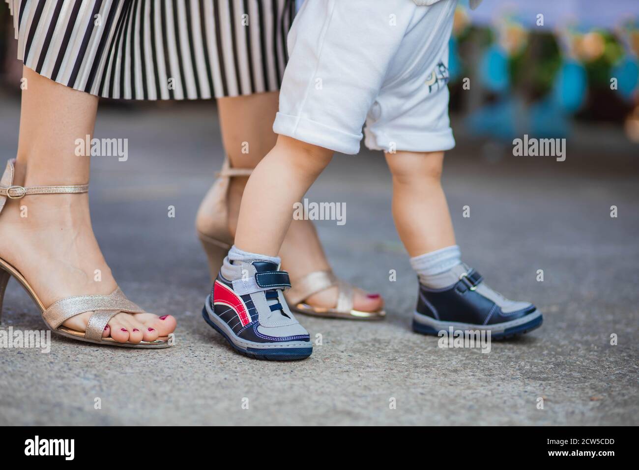 Mom helping her baby son to walk. Parenting concept Stock Photo