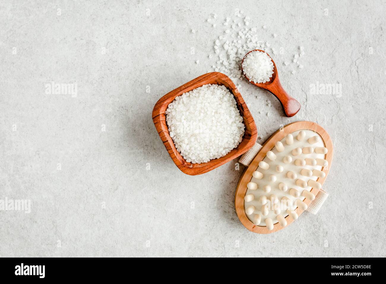 Spa skincare concept. Natural Organic spa cosmetics products, sea salt, massage brush and tropic palm leaves on gray marble table from above.  Stock Photo