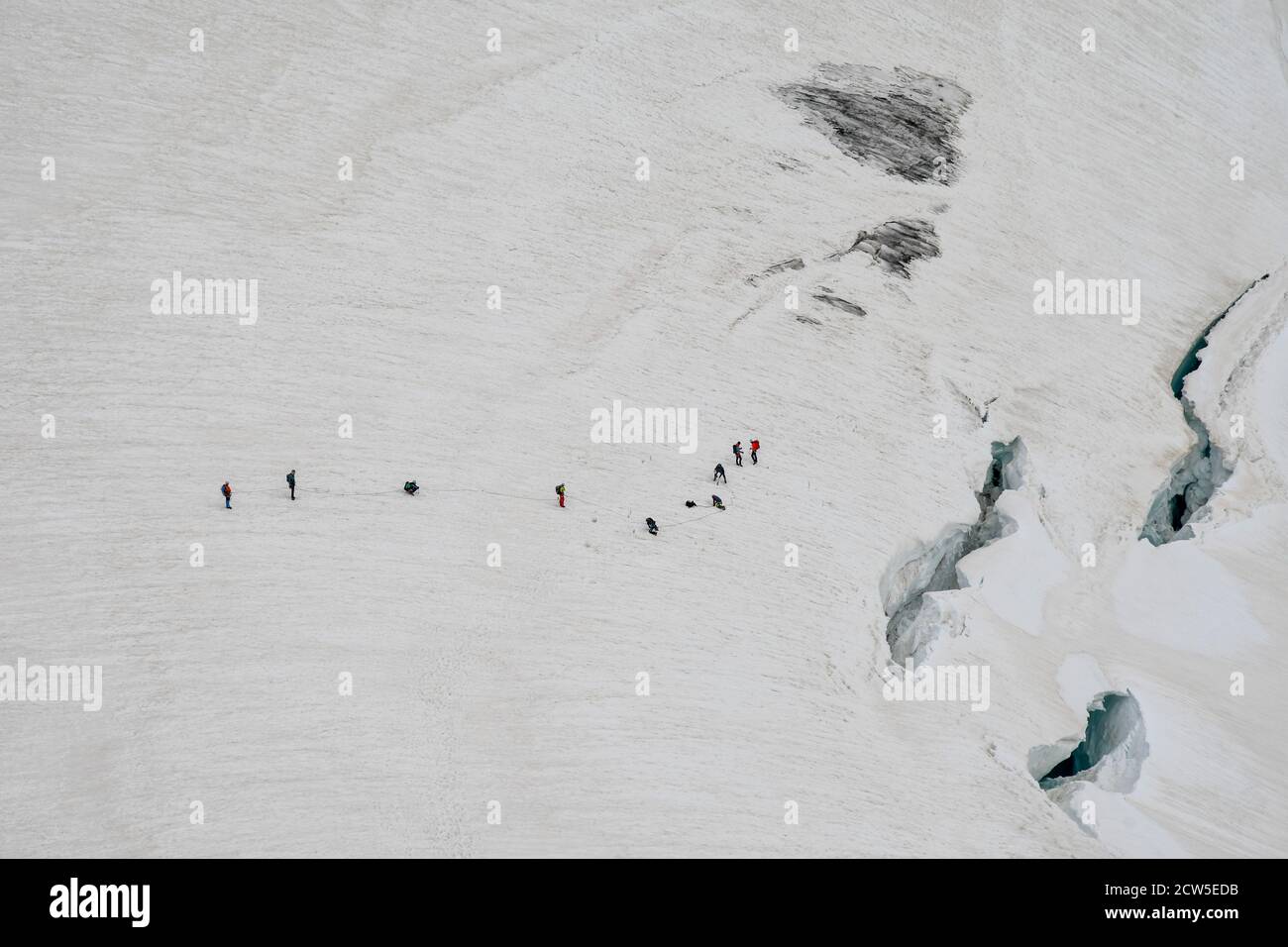 Roped climbing party on the perennial glacier of Mont Blanc massif near crevasses, French-Italian border, Alps, Courmayeur, Aosta Valley, Italy Stock Photo