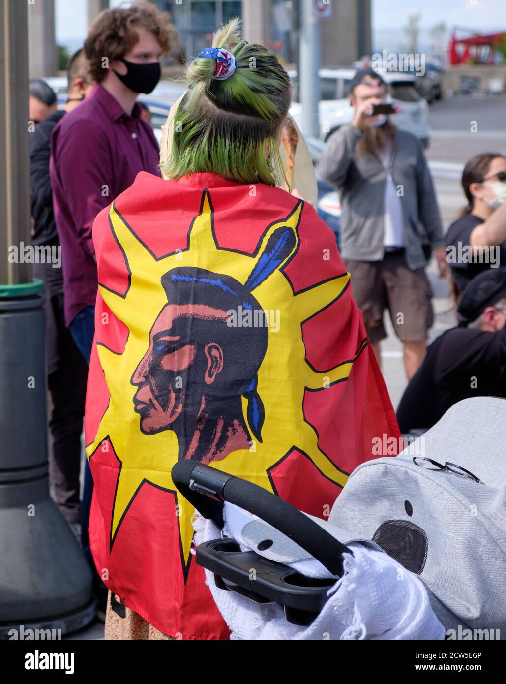 First Nations  woman at protest outside Canadian Senate wrapped in warrior flag, seen from behind Stock Photo