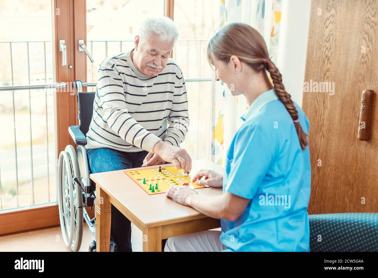 Nurse and senior in retirement home playing a board game Stock Photo