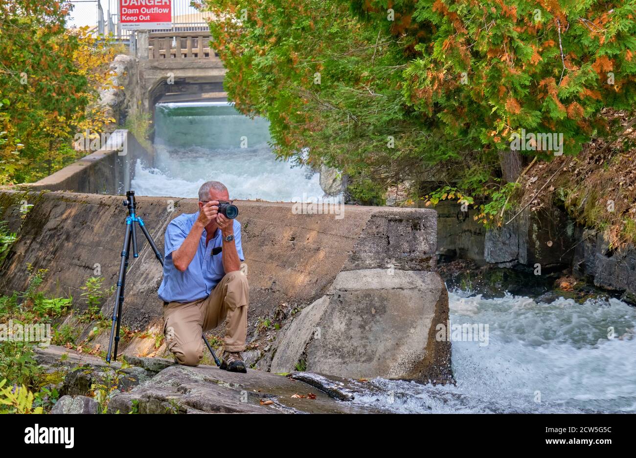 Photographer sets up his shot near the log chute sluiceway at Buttermilk falls in Haliburton County Ontario. Stock Photo