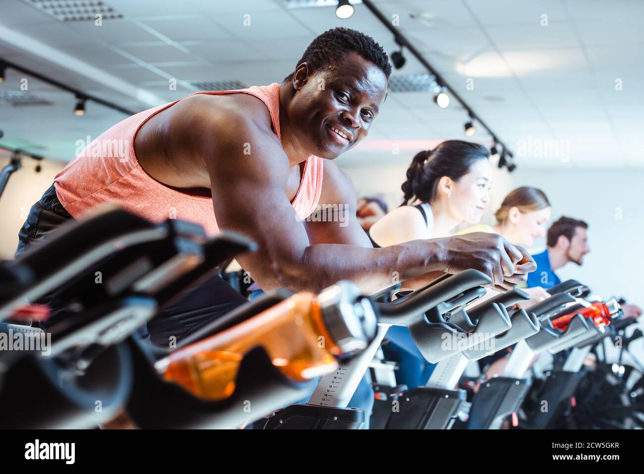 African man and friends on fitness bike in gym Stock Photo