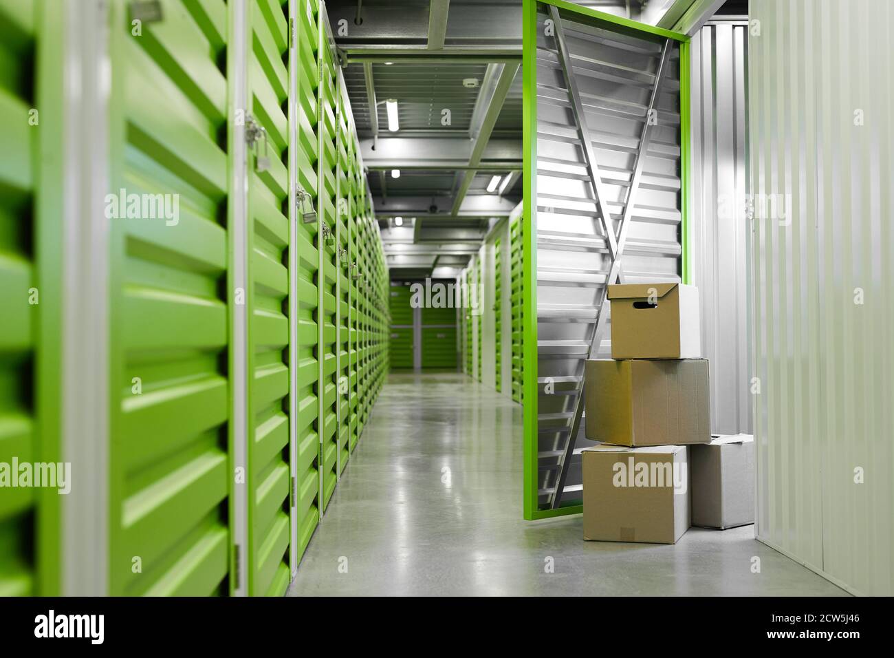 Background image of green self storage facility with opened unit door and cardboard boxes, copy space Stock Photo