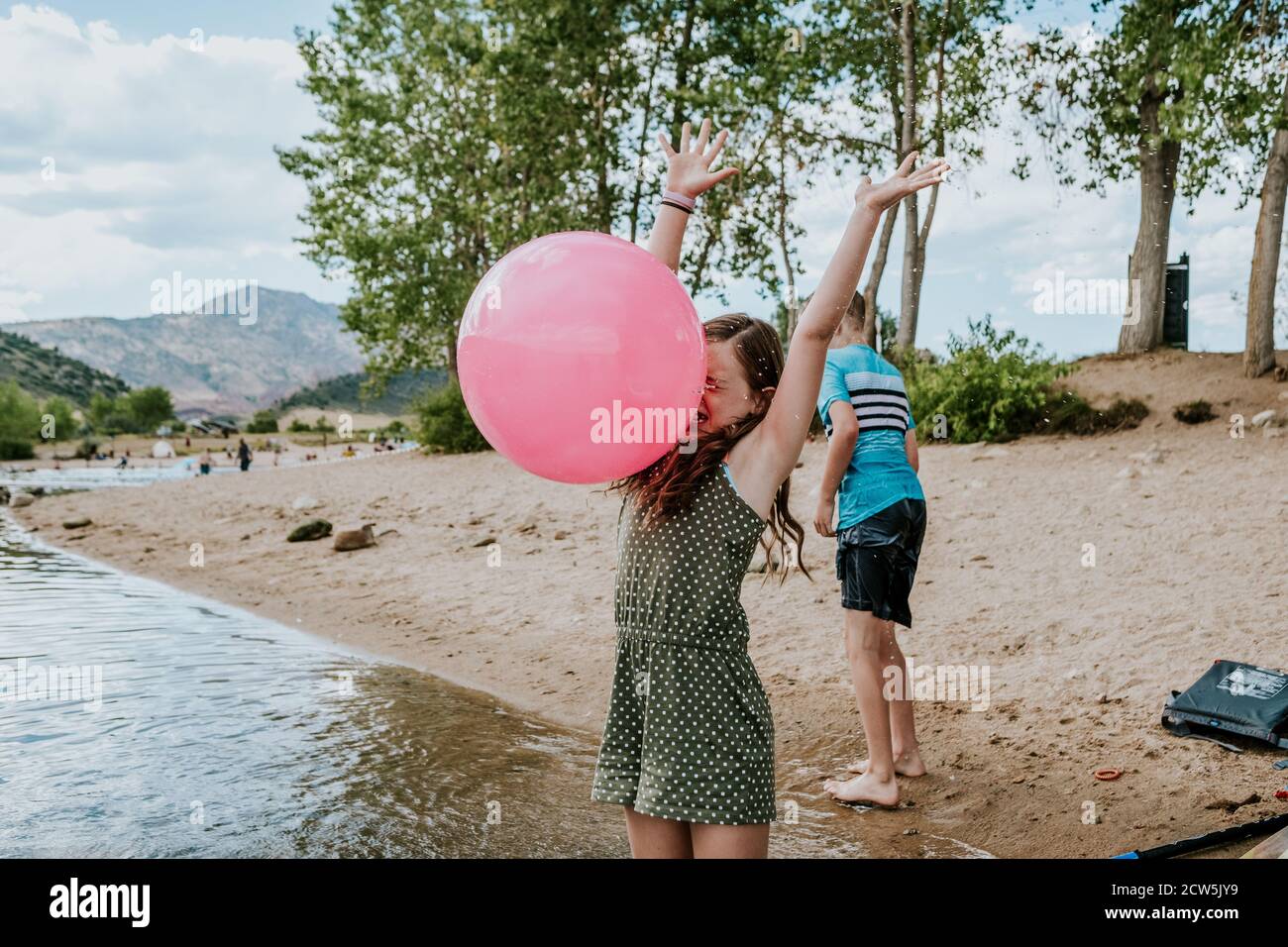 Young girl getting hit in the face with a large ball on a summer day