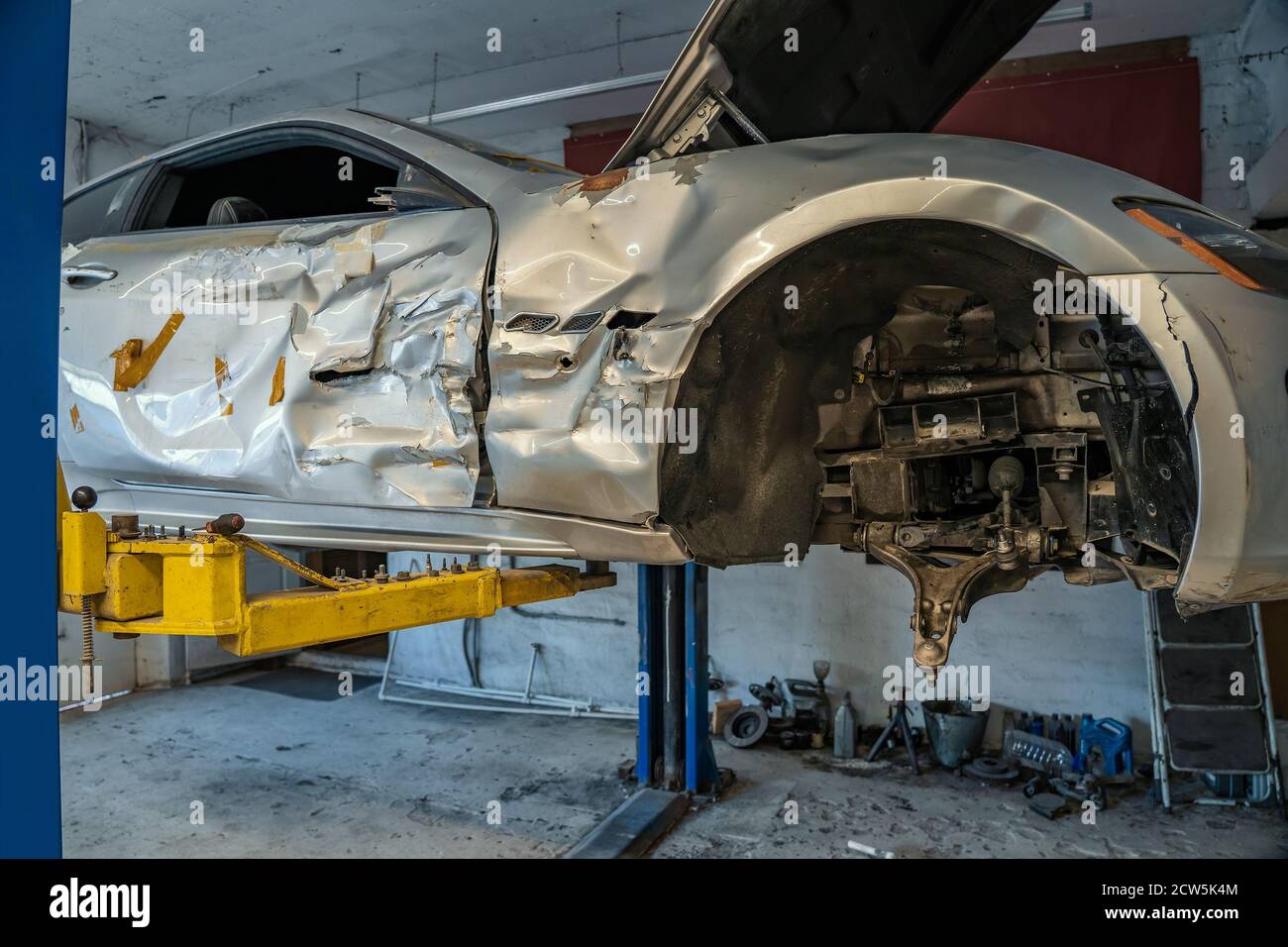 Broken or damaged sport car after road accident or crash in garage repair service shop, close up