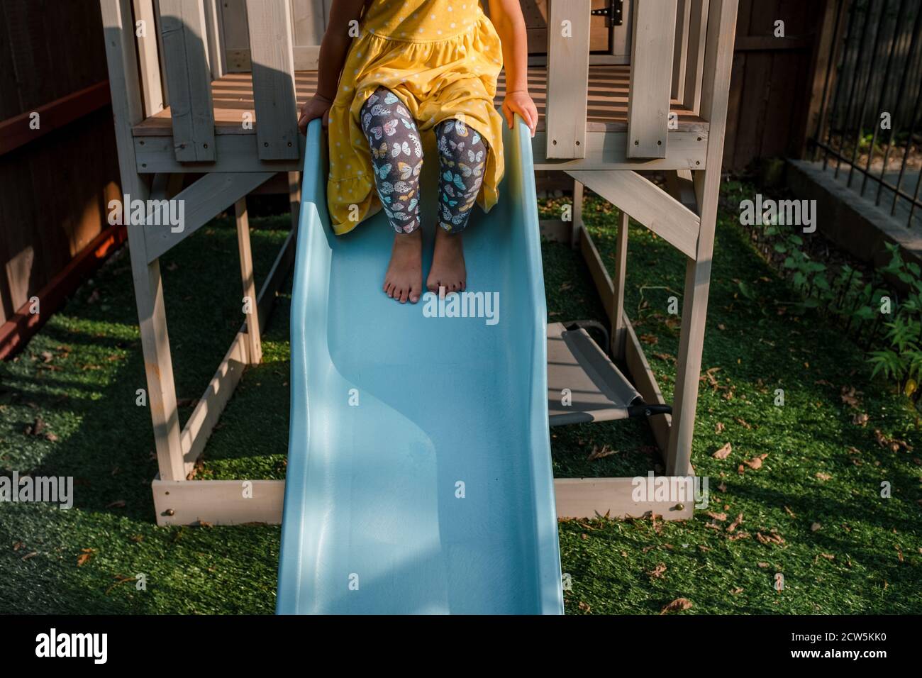 Child sitting at the top of a blue slide Stock Photo