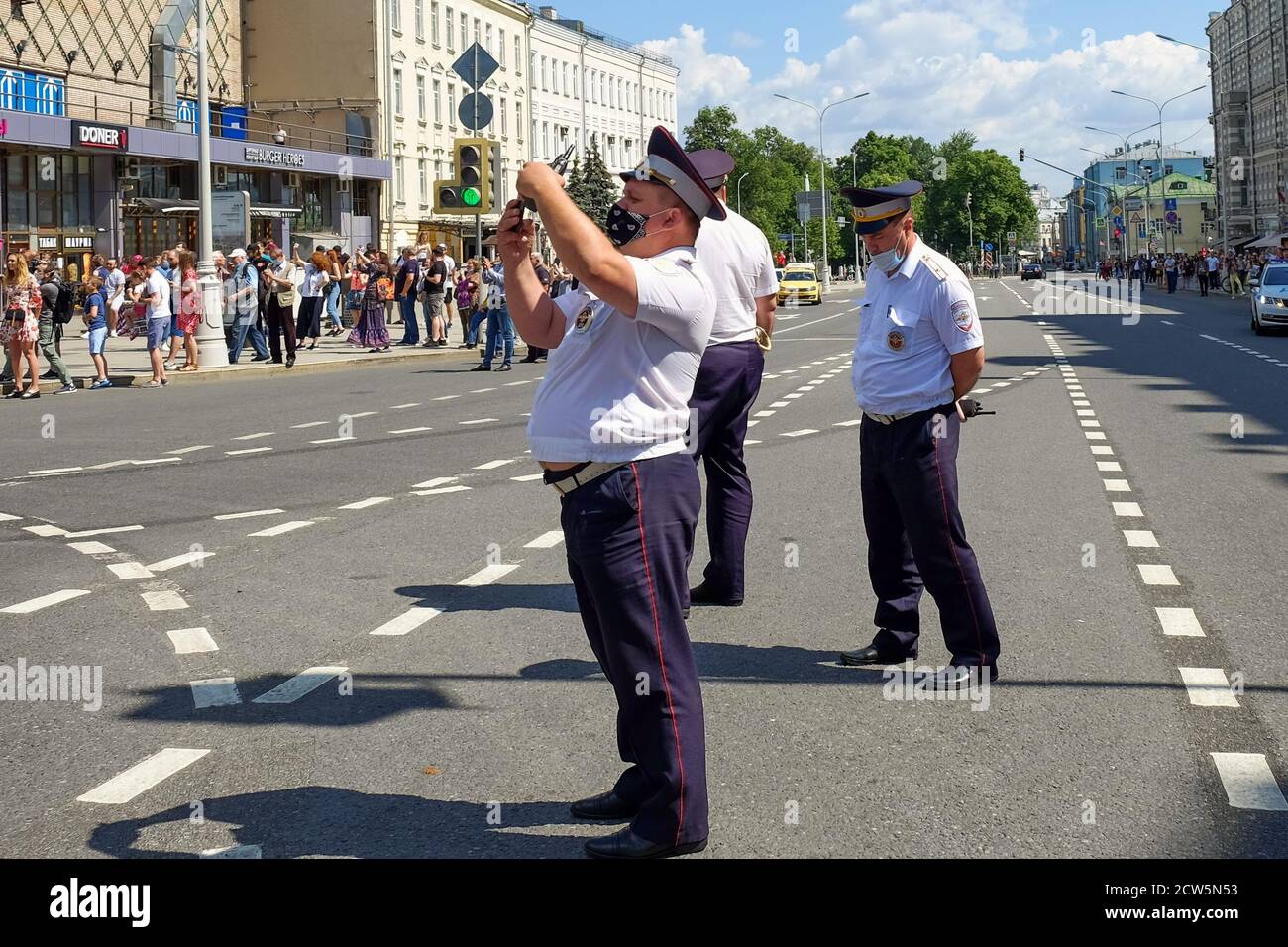 Group of tired policemen in summer uniforms and protective masks patrol city streets during global pandemic. Stock Photo
