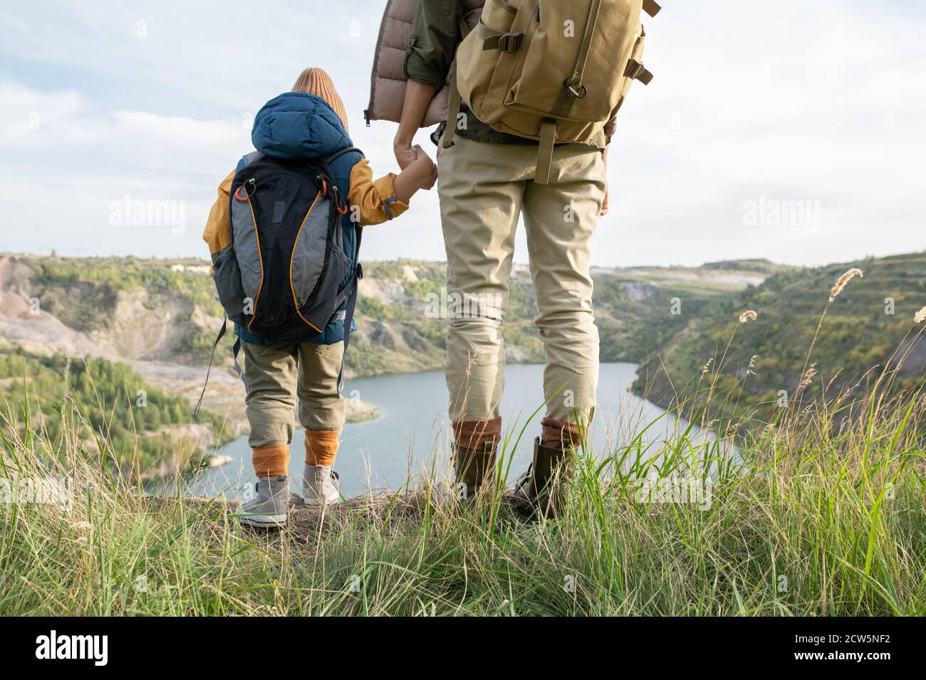 Rear view of young woman and her little son with backpacks holding by hands Stock Photo