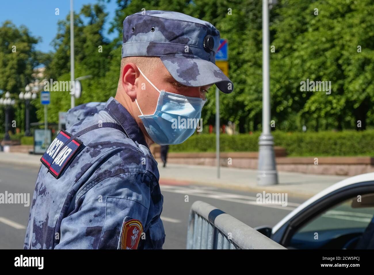 Young soldier of Russia Guard wearing summer camouflage, protective mask and gloves working on the street.Moscow, Russia,June 2020.  Stock Photo