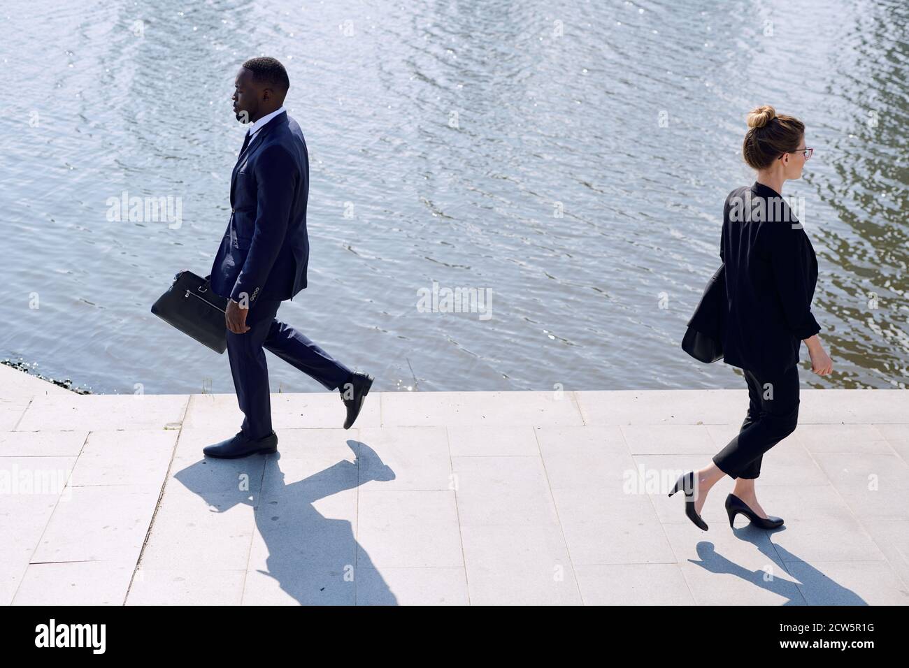 Contemporary business people in formalwear passing by each other by eiverside Stock Photo