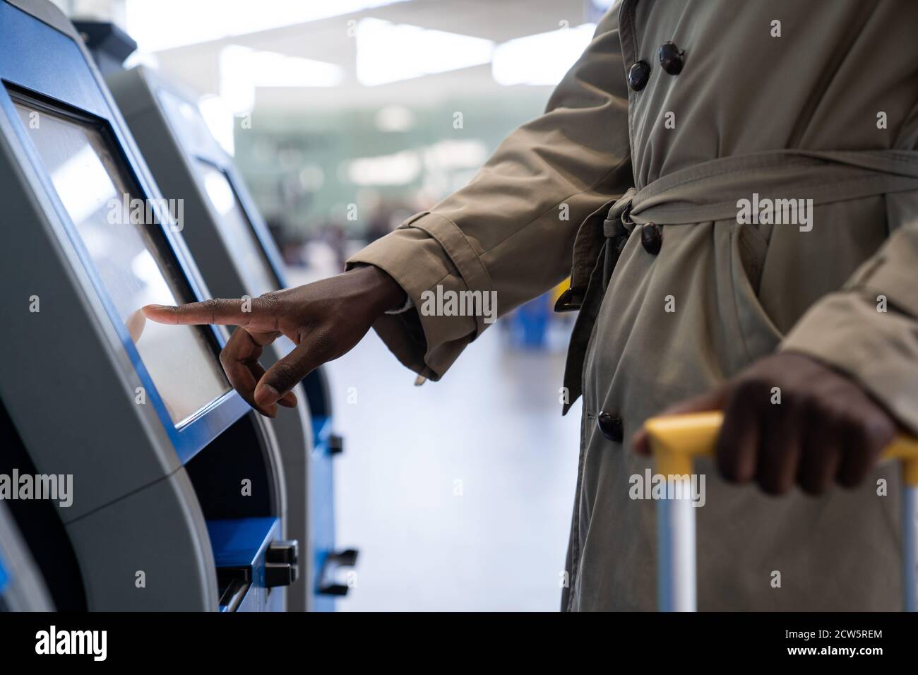 Black traveler man using self check-in machine kiosk service at airport, finger point on display. Close up. Stock Photo