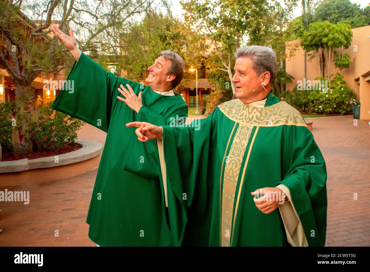 Wearing green ceremonial robes, a deacon and a monsignor strike a ...