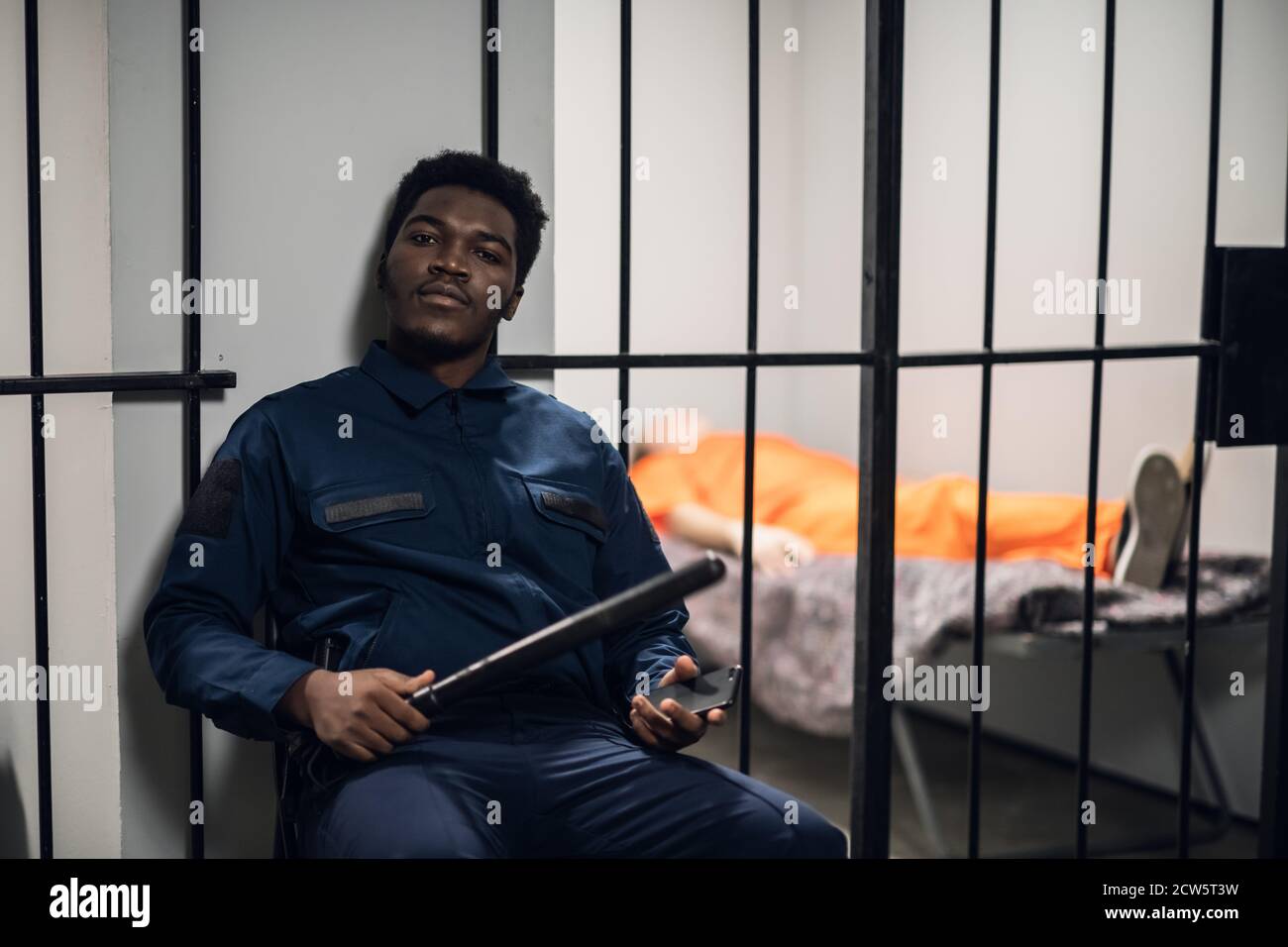 A prison warden guards cells with prisoners sentenced to life in orange