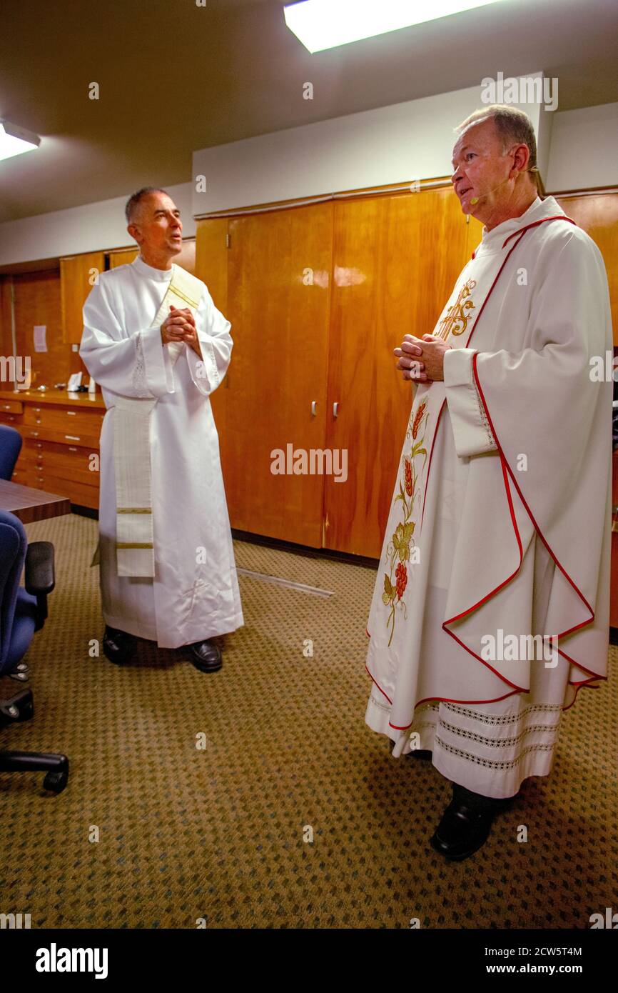 Wearing ceremonial robes, a priest and his deacon confer while preparing for mass at a Southern California Catholic church. Stock Photo