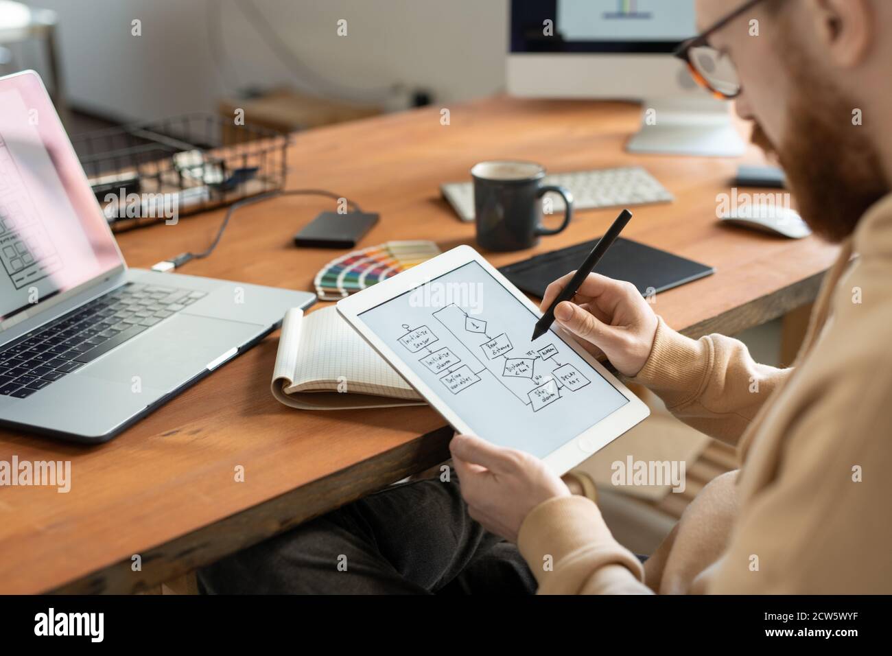 Young bearded freelance programmer holding stylus over touchscreen Stock Photo