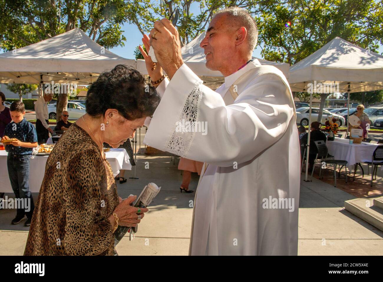 After mass, the deacon of a Southern California Catholic church gives his blessing to an Asian American parishioner in the church outdoor yard. Stock Photo