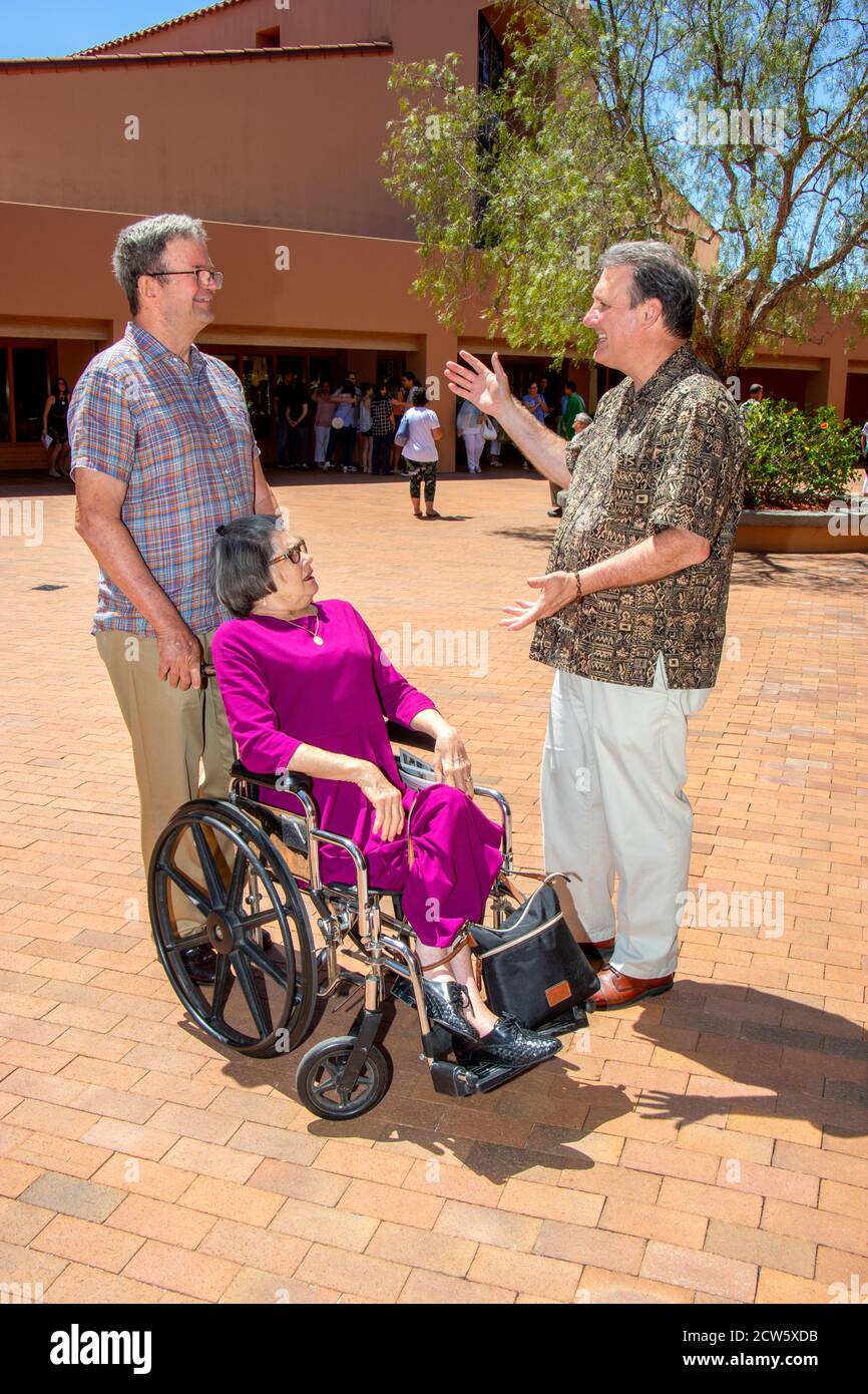 The deacon of a Southern California Catholic church greets a wheelchair-bound parishioner after mass in the church courtyard. Stock Photo