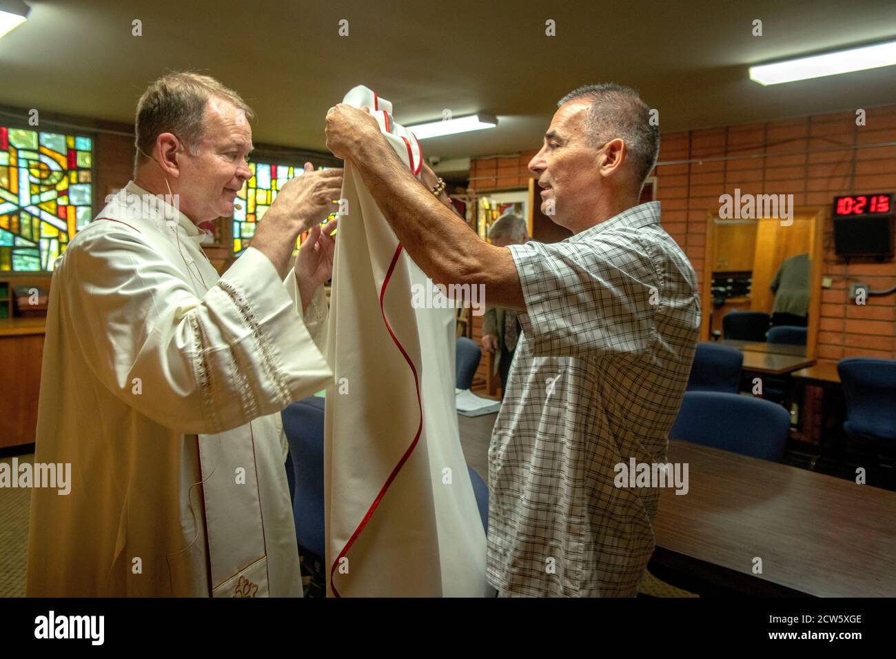 The deacon of a Southern California Catholic church helps to dress his priest in ceremonial vestments before mass. Stock Photo