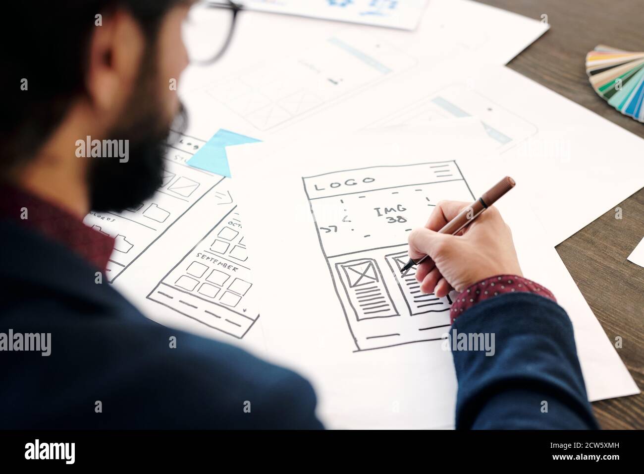 Hand of young male developer of mobile application holding pencil over ...