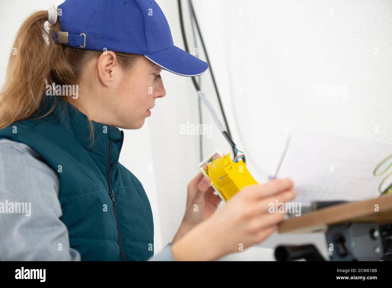 female builder with screwdriver fixing socket indoors Stock Photo