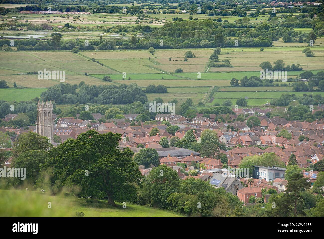 Glastonbury town seen from a local hilltop. Red roofs cluster in the township with surrounding hedged farmland. Pilgrimage site for New Agers. Stock Photo