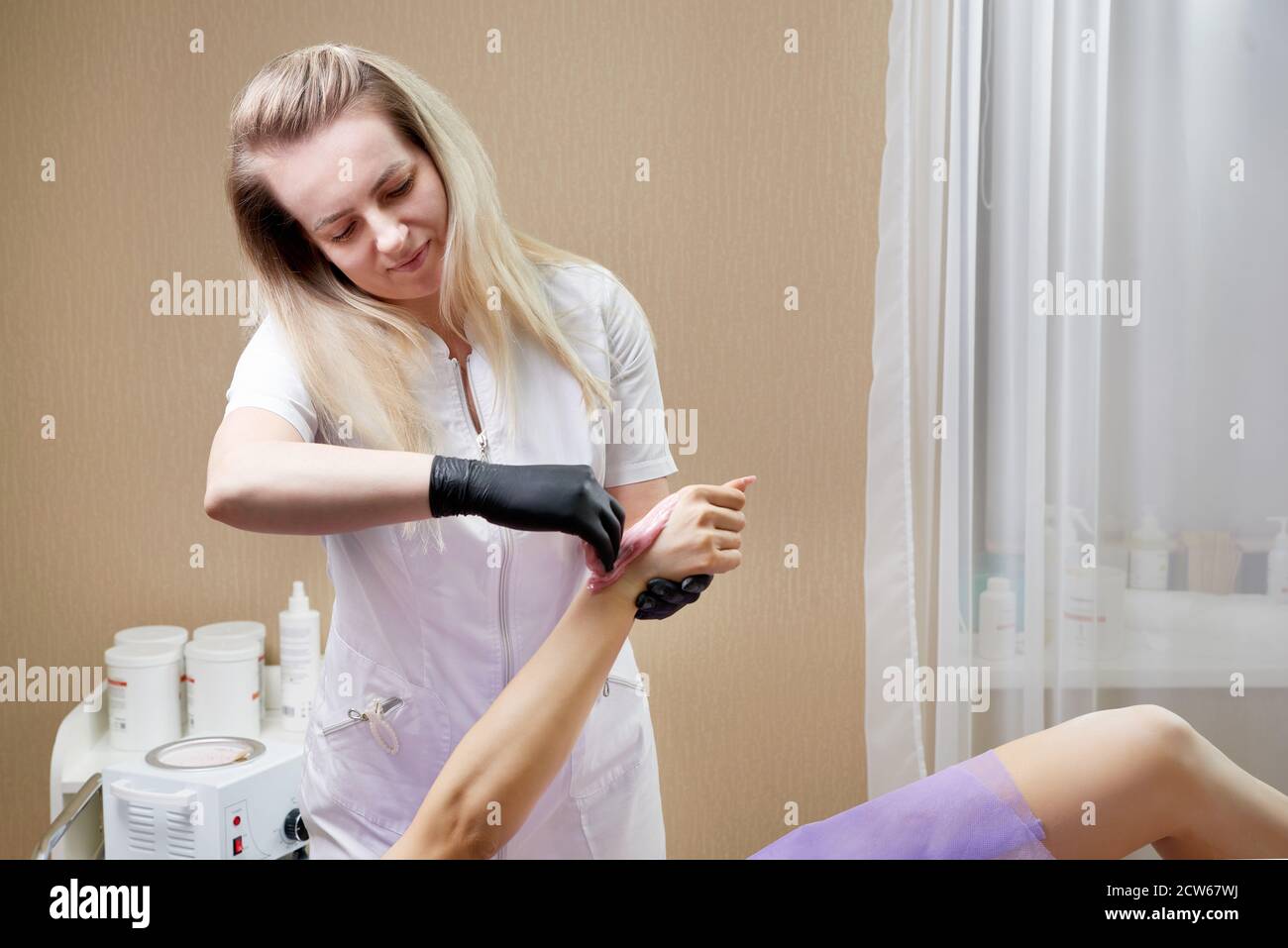 Process of waxing in a beauty salon by a professional beautician. Beauty salon worker applying