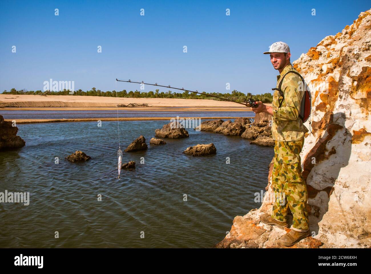 A solo adventure angler fishing around sandstone rock formations along the Mitchell River in Queensland, Australia. Stock Photo