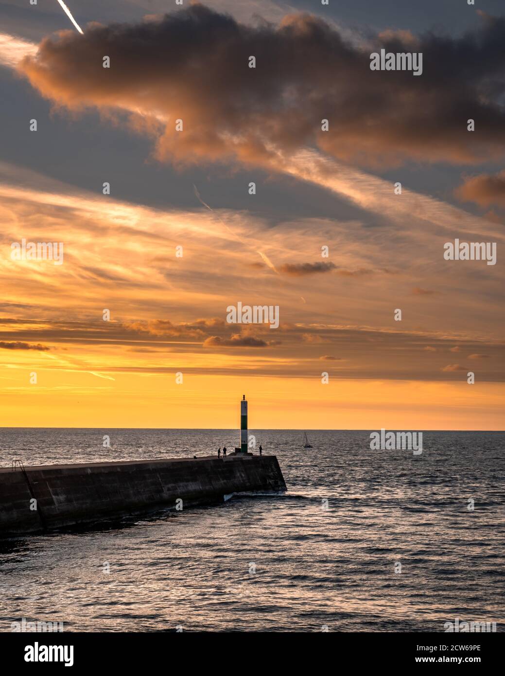 Sunset in Aberystwyth on the welsh coast while people fish in the last light of the day. Stock Photo