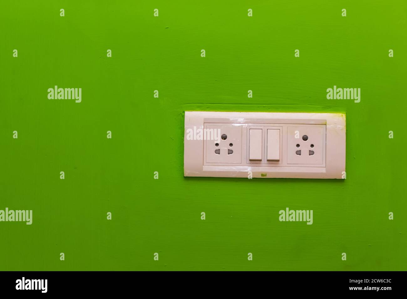 Double Sockets for electrical appliances on a green wall background