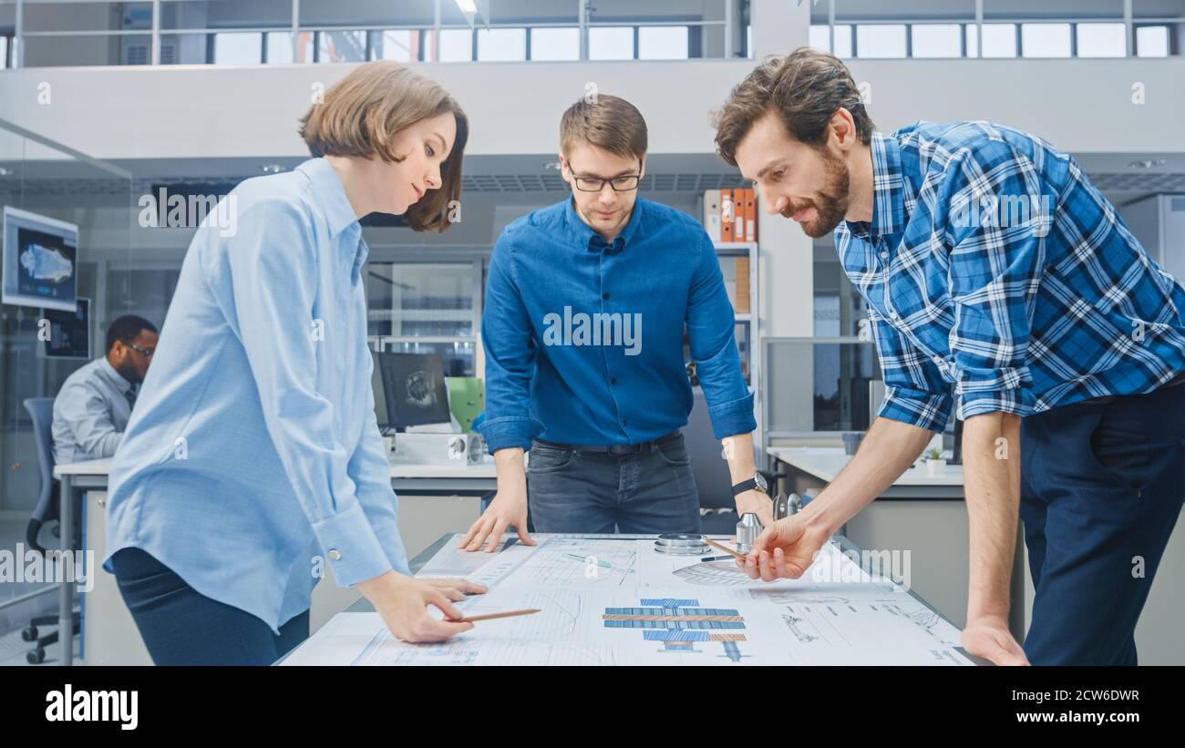 In the Industrial Engineering Facility: Female Designer Works with Industrial Engineer and Master Technician, They have Discussion, Analyse Engine Stock Photo