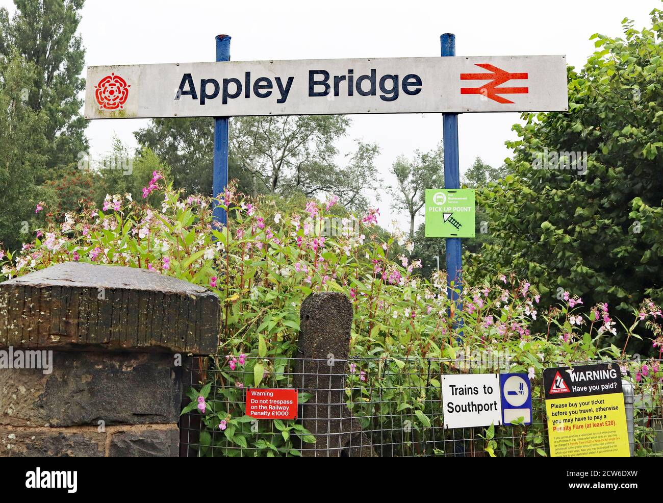 The station sign’s at Appley Bridge on a wet morning in Greater Manchester.  The signs still include the old British Railways Double Arrow symbol. Stock Photo