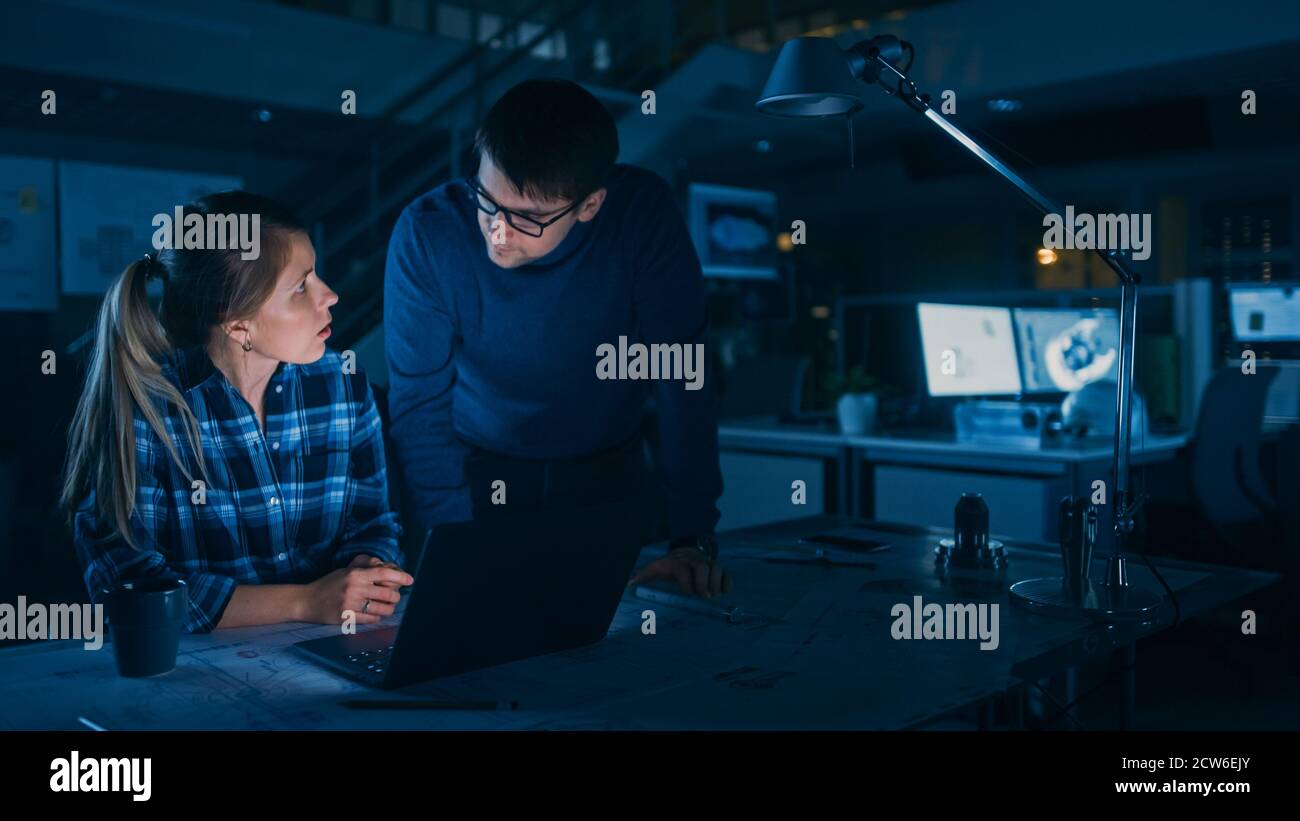 Industrial Engineering Facility: Female Engineer Working on Desktop Computer, Project Manager Stands Beside and Explains Specifics of the Task and Stock Photo