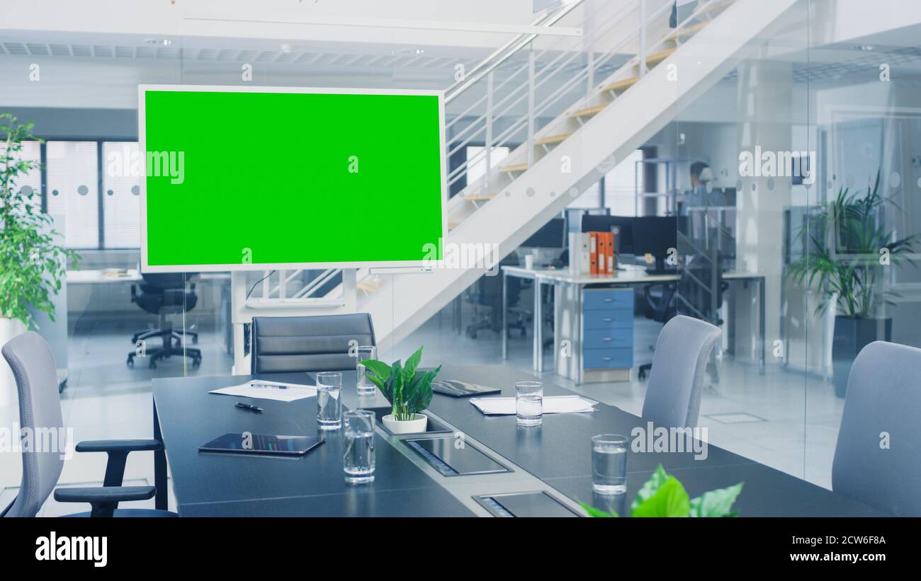 In the Corporate Office Meeting Room Stands Green Mock-up Screen TV or Interactive Digital Whiteboard in Horizontal Mode. In the Background Big Bright Stock Photo