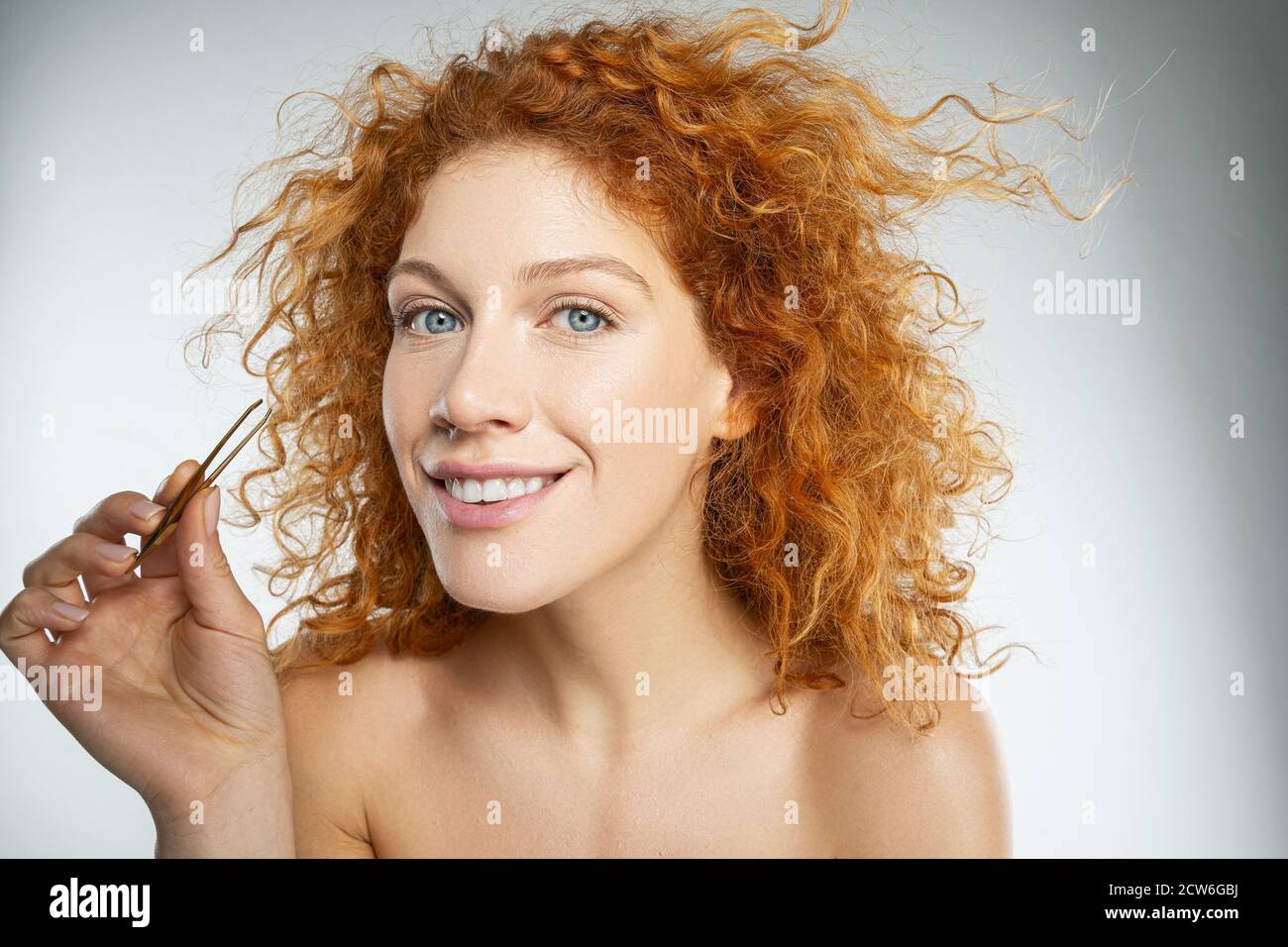 Young woman using pliers on her eyebrow Stock Photo