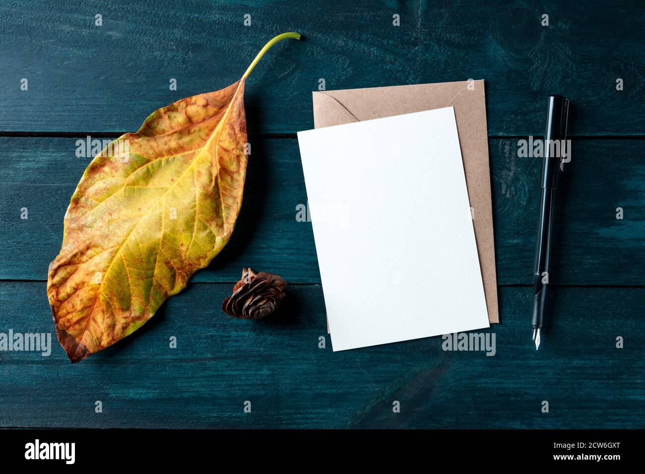 A vertical A5 greeting card or invitation, autumn stationery mockup, flatlay, top shot on a dark blue wooden background Stock Photo
