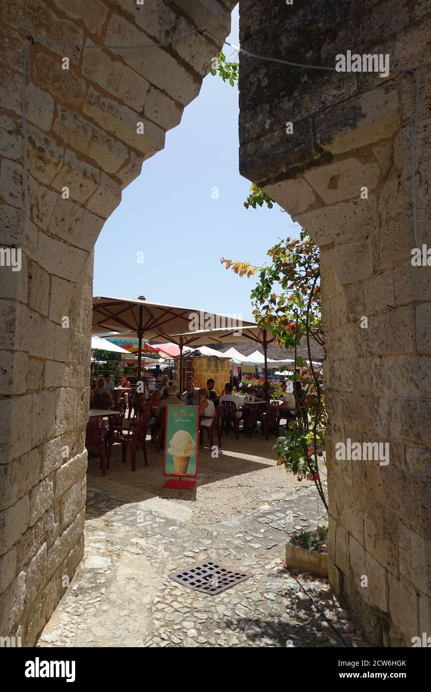 Monpazier, France July 2020: A restaurant in the town square of Monpazier, seen through a gap in the stone arcades Stock Photo