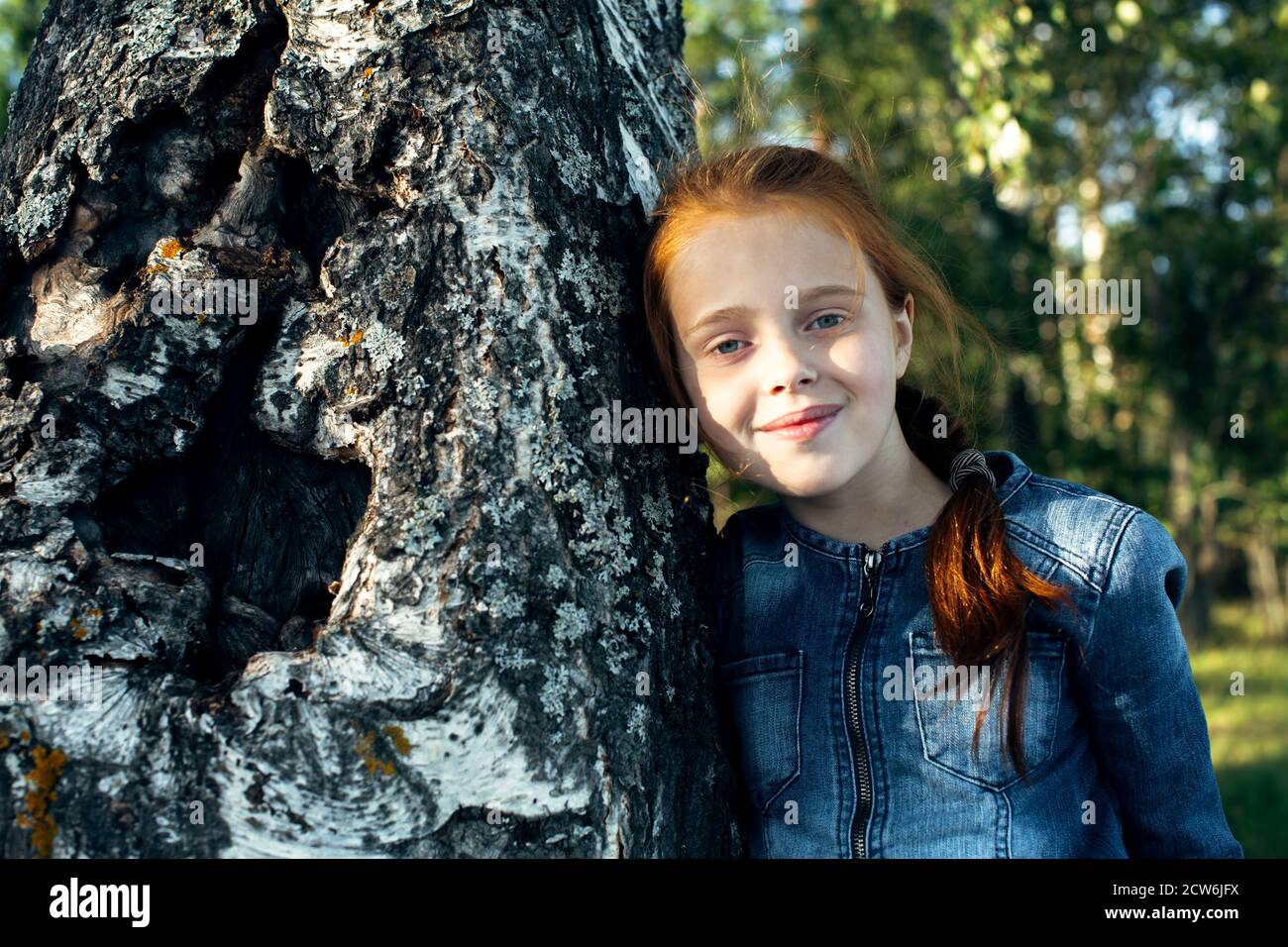 Teen girl sitting in the woods near birch Stock Photo - Alamy