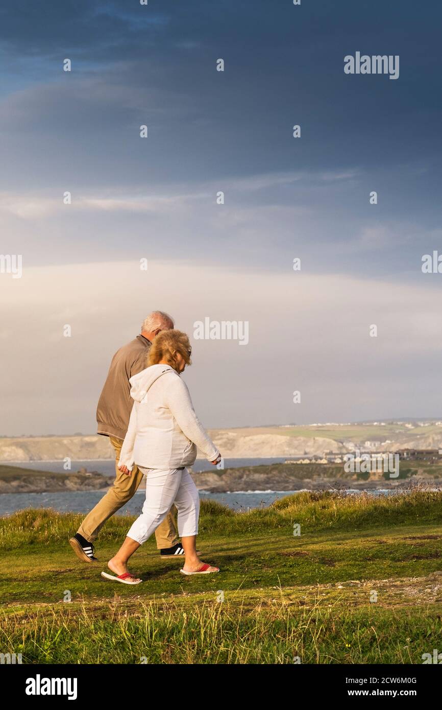 A mature couple of holidaymakers enjoying a late evening stroll along Pentire Point East in Newquay in Cornwall. Stock Photo