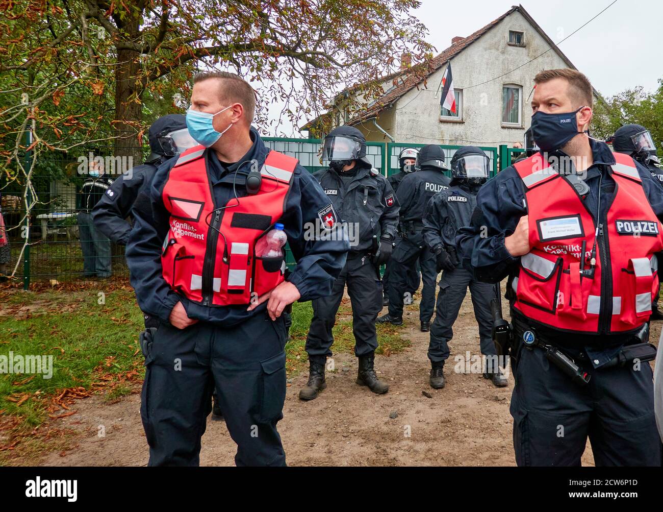 Eschede, Germany, September 26., 2020: Officers for conflict management with red vests without helmets stand in front of the block with black uniforme Stock Photo