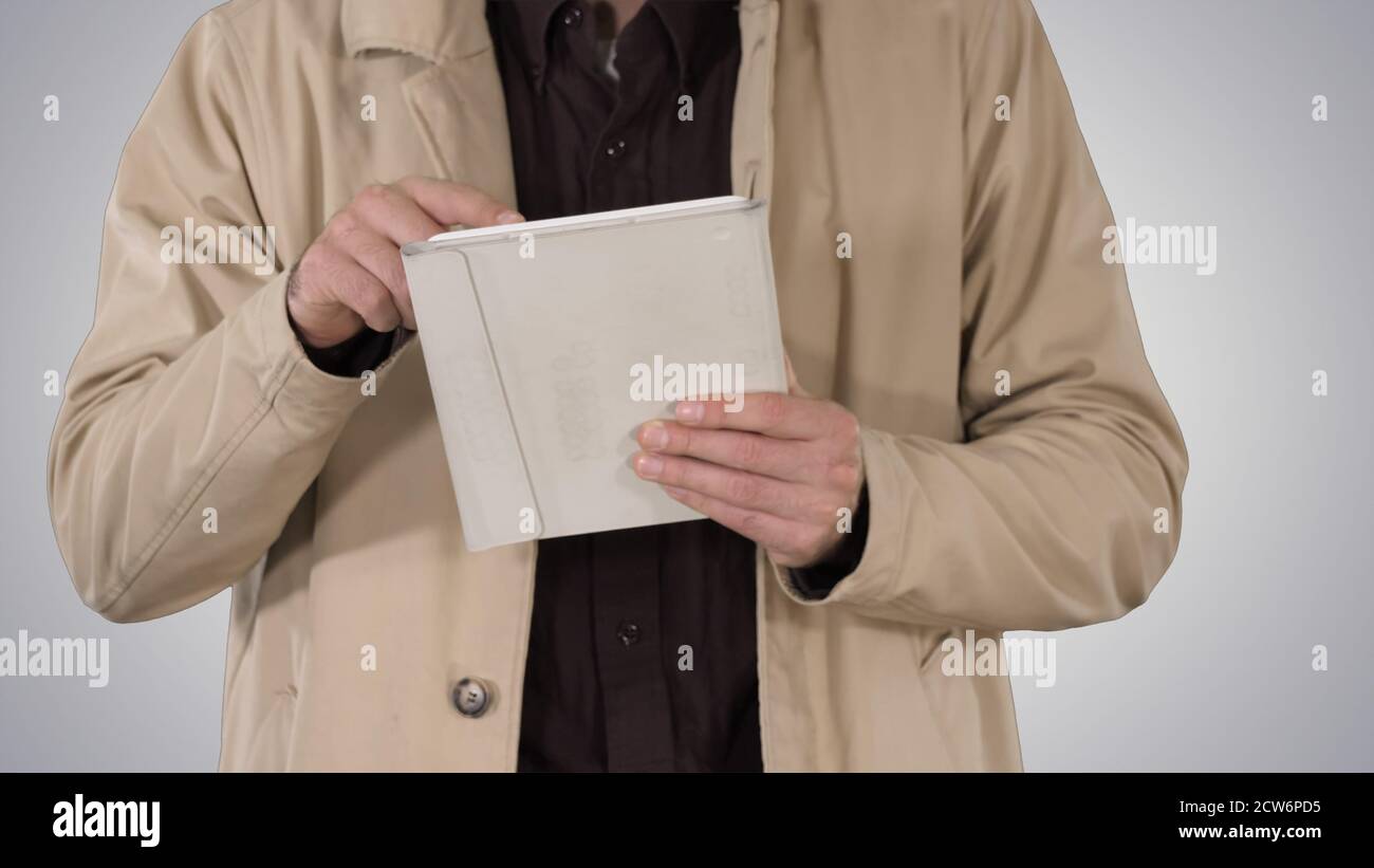 Hands of man using tablet on gradient background. Stock Photo