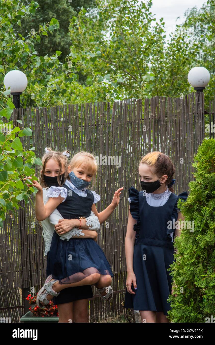Three schoolgirls wearing masks and going back to school during covid ...
